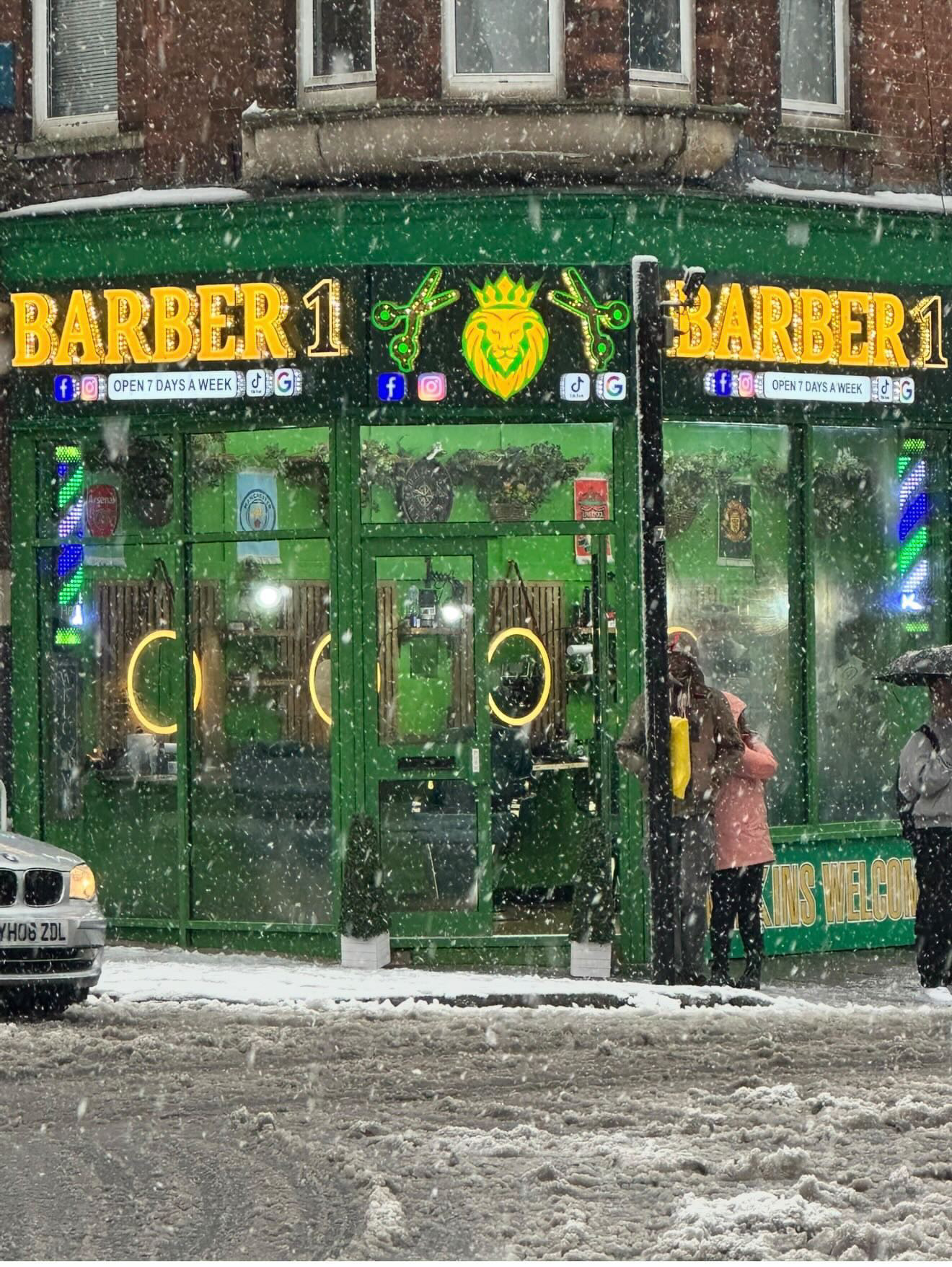 Barber 1 shopfront in the snow — bold green facade with gold signage